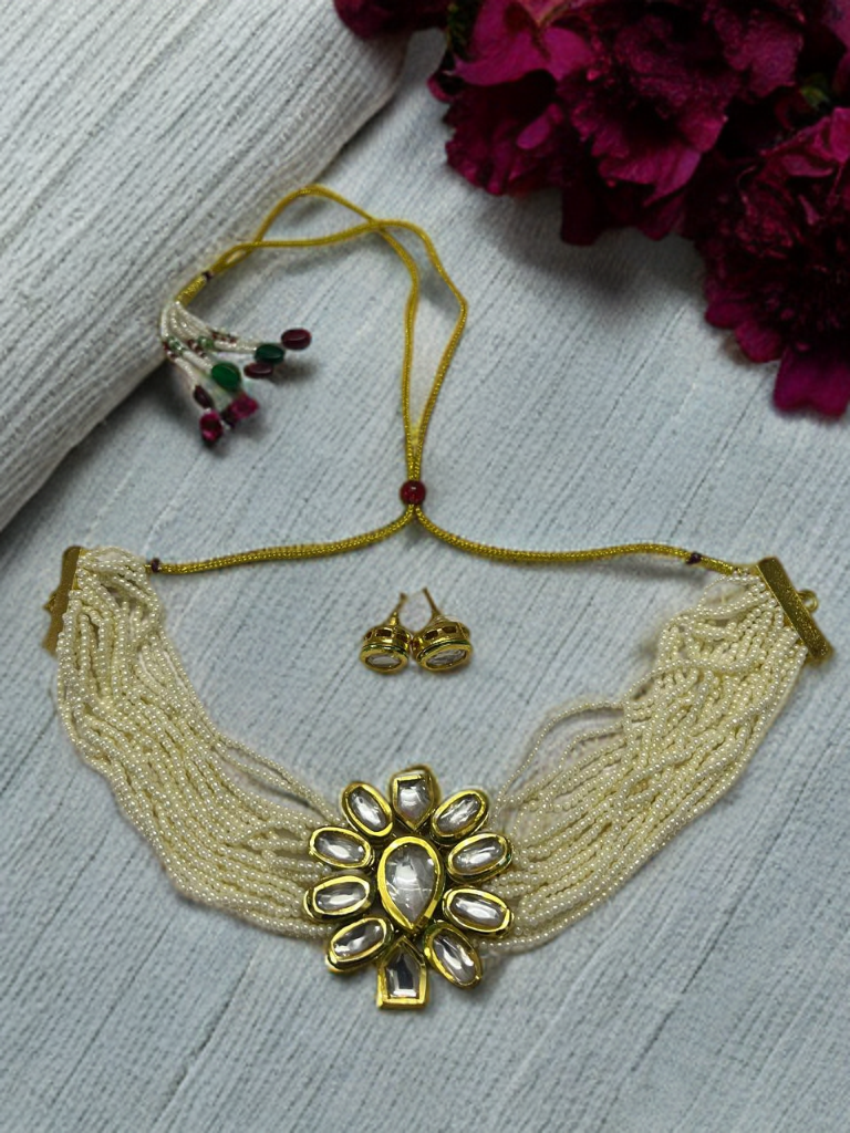 Beaded necklace with floral design and matching earrings on a textured surface.